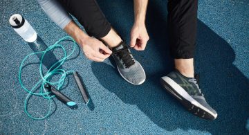 persona con abbigliamento sportivo mentre si allaccia le scarpe su una pista