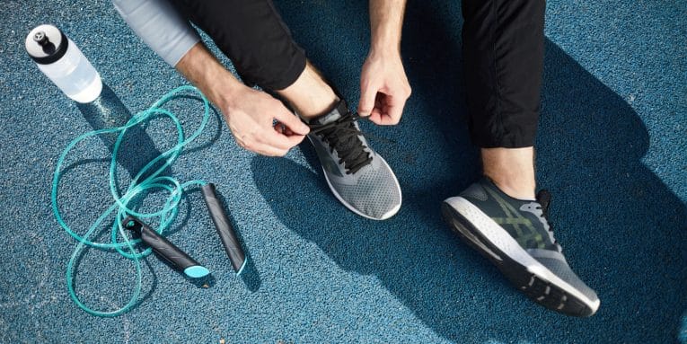 persona con abbigliamento sportivo mentre si allaccia le scarpe su una pista