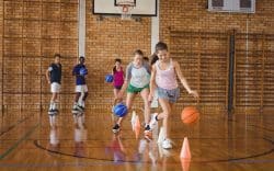 studenti con abbigliamento sportivo mentre fanno esercizi di basket in palestra