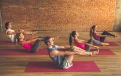 gruppo di persone esegue esercizi di ginnastica posturale su tappetino in palestra