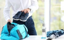 persona con in mano scarpe sportive prepara borsa da palestra
