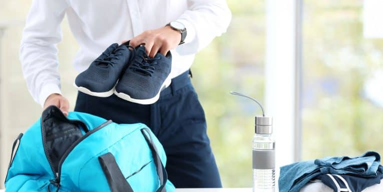 persona con in mano scarpe sportive prepara borsa da palestra