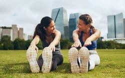 due donne fanno stretching all’aperto sedute sull’erba