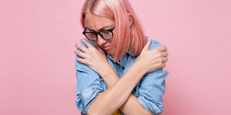 donna con dolore tiene le braccia incrociate mostrando disagio