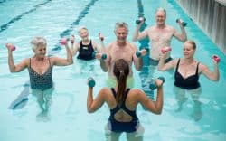 gruppo di persone fa acquagym in piscina guidato da istruttrice
