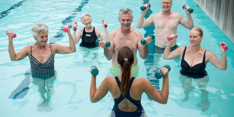 gruppo di persone fa acquagym in piscina guidato da istruttrice