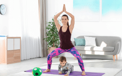 donna si allena a casa su tappetino con bambino durante esercizi fitness