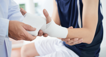 Persona con il braccio fasciato mentre viene medicata da un medico.