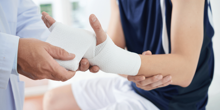 Persona con il braccio fasciato mentre viene medicata da un medico.