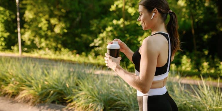 Donna beve caffè durante un allenamento all’aperto