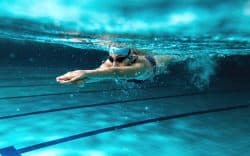 Persona che nuota sott’acqua in una piscina.