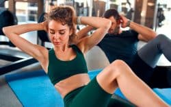 persone che fanno esercizi addominali su tappetini in palestra