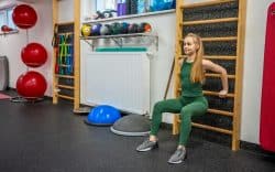 Donna che esegue esercizi alla spalliera in palestra