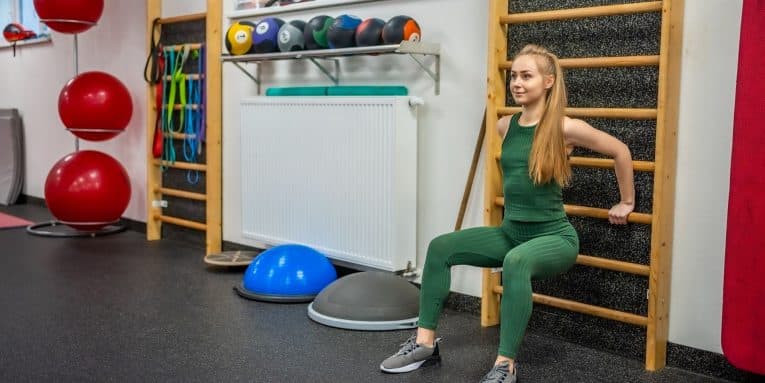Donna che esegue esercizi alla spalliera in palestra