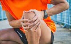 Persona con le mani sul ginocchio in segno di dolore
