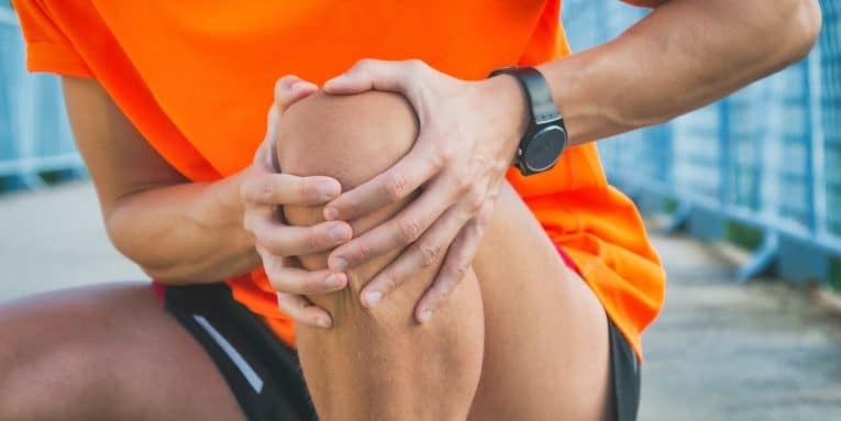 Persona con le mani sul ginocchio in segno di dolore