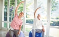 anziani che fanno esercizi di stretching seduti su palle fitness