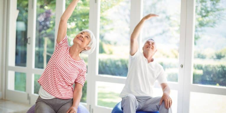 anziani che fanno esercizi di stretching seduti su palle fitness