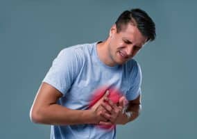 Uomo che si tiene il petto con espressione dolorante