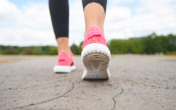 Dettaglio scarpe di persona che cammina su strada asfaltata.