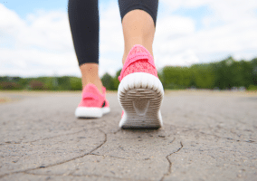 Dettaglio scarpe di persona che cammina su strada asfaltata.