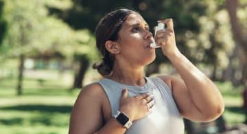 Donna all’aperto mentre utilizza un inalatore per l'asma