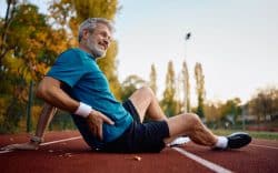 Uomo a terra su una pista di atletica mentre si tiene il fianco
