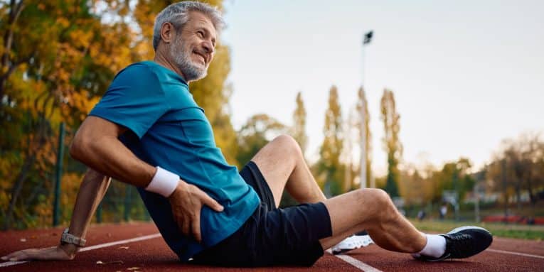 Uomo a terra su una pista di atletica mentre si tiene il fianco