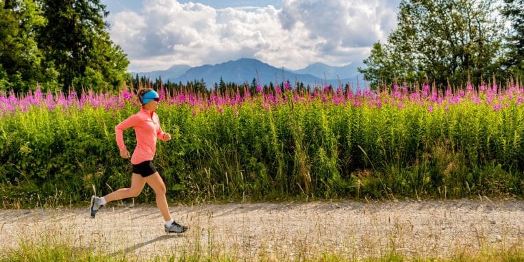 Donna che corre lungo un sentiero di campagna immerso nella natura