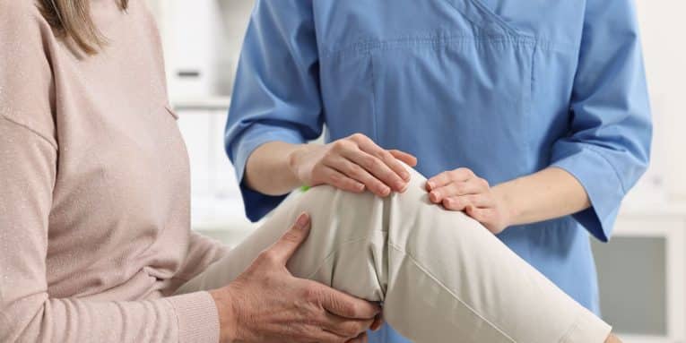 Operatore sanitario che visita una paziente con dolore al ginocchio