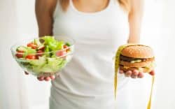 Donna che tiene in mano una ciotola di insalata e un hamburger