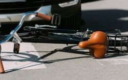 Bicicletta caduta a terra vicino a un’auto