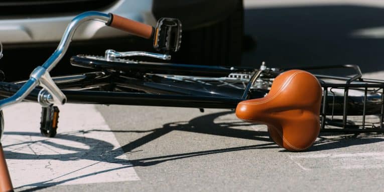 Bicicletta caduta a terra vicino a un’auto