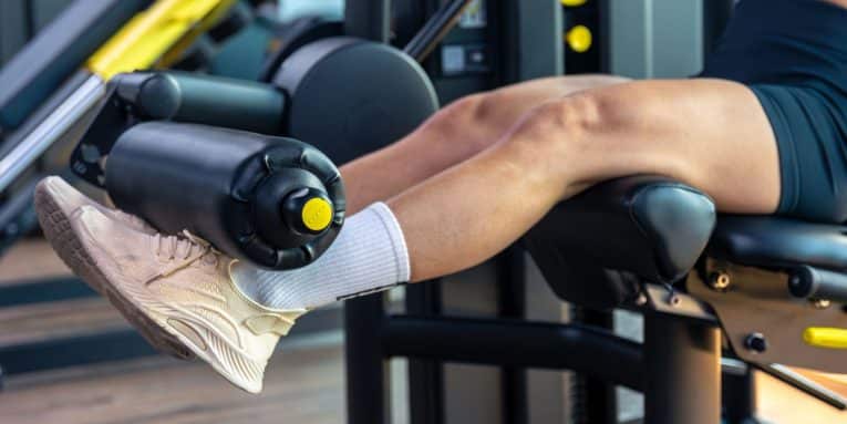 Persona che si allena in palestra con una macchina per esercizi alle gambe