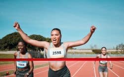 Atleta che taglia festeggiando il traguardo per prima durante una gara di corsa su pista