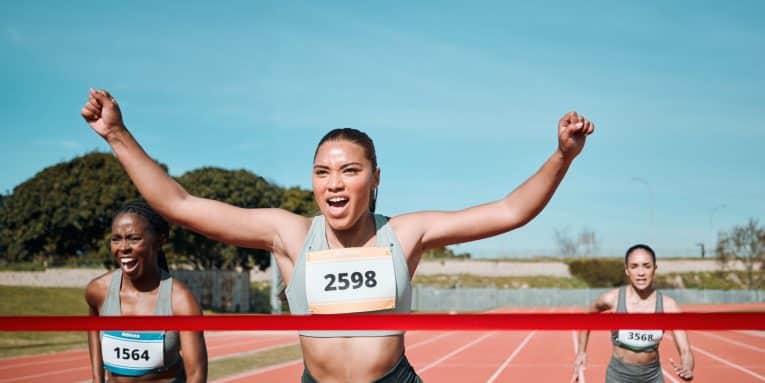 Atleta che taglia festeggiando il traguardo per prima durante una gara di corsa su pista