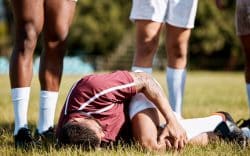 Calciatore a terra durante una partita mentre si tiene il ginocchio