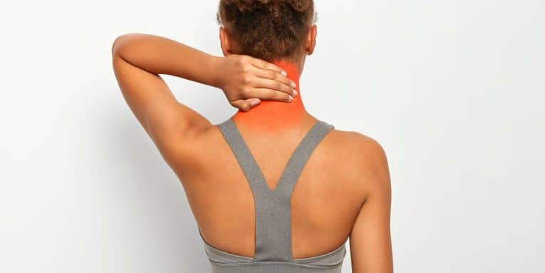 Donna vista di schiena che si tocca il collo evidenziando un dolore cervicale