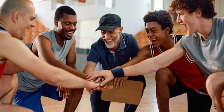 Allenatore e squadra di basket in palestra durante un momento di motivazione