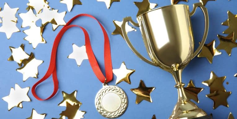Coppa dorata e medaglia sportiva con nastro rosso su sfondo blu decorato con stelle