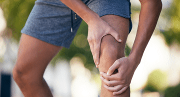 Persona che tiene il ginocchio con entrambe le mani a causa di un dolore