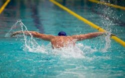 Persona che nuota in piscina all’interno di una corsia