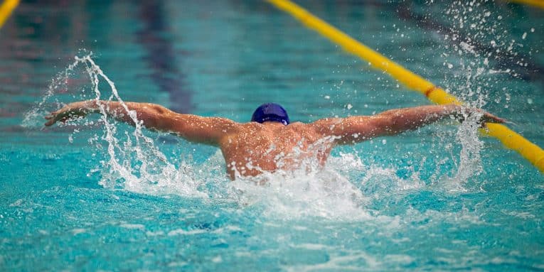 Persona che nuota in piscina all’interno di una corsia