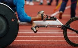 Dettaglio di atleta paralimpico in carrozzina durante una gara su pista di atletica.