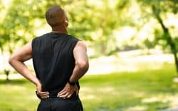 Uomo sportivo all’aperto che si tiene la parte bassa della schiena in segno di dolore