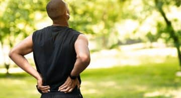 Uomo sportivo all’aperto che si tiene la parte bassa della schiena in segno di dolore