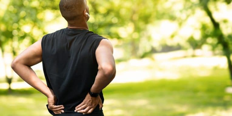Uomo sportivo all’aperto che si tiene la parte bassa della schiena in segno di dolore