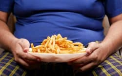 Persona seduta con un piatto di patatine fritte in mano.