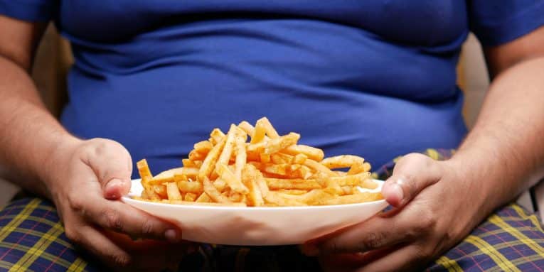Persona seduta con un piatto di patatine fritte in mano.