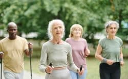 Gruppo di persone anziane durante una camminata sportiva all’aperto in un parco.